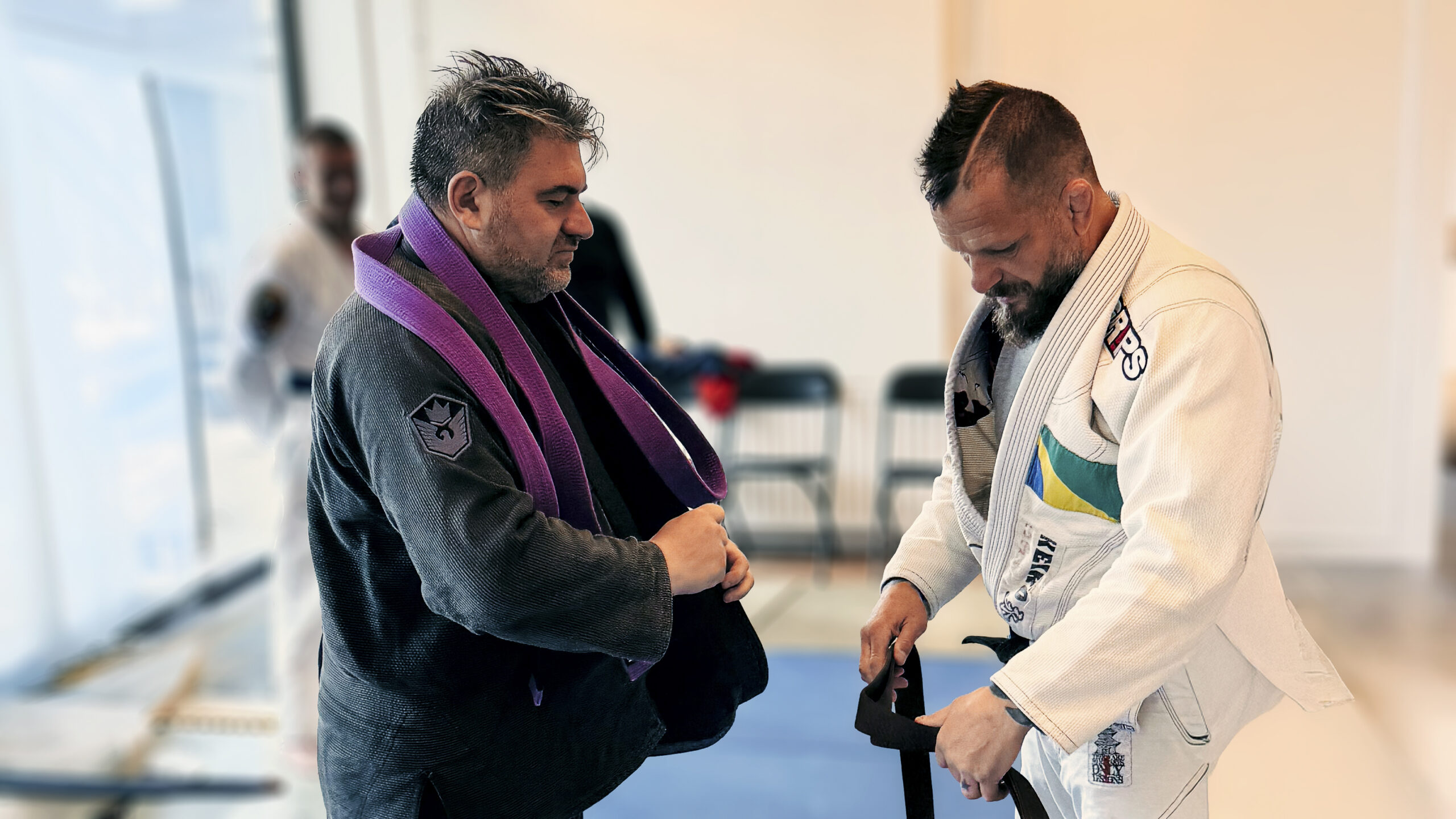 Christian Vernaschi receiving a new BJJ belt from Master Cesario Di Domenico in a martial arts promotion ceremony.