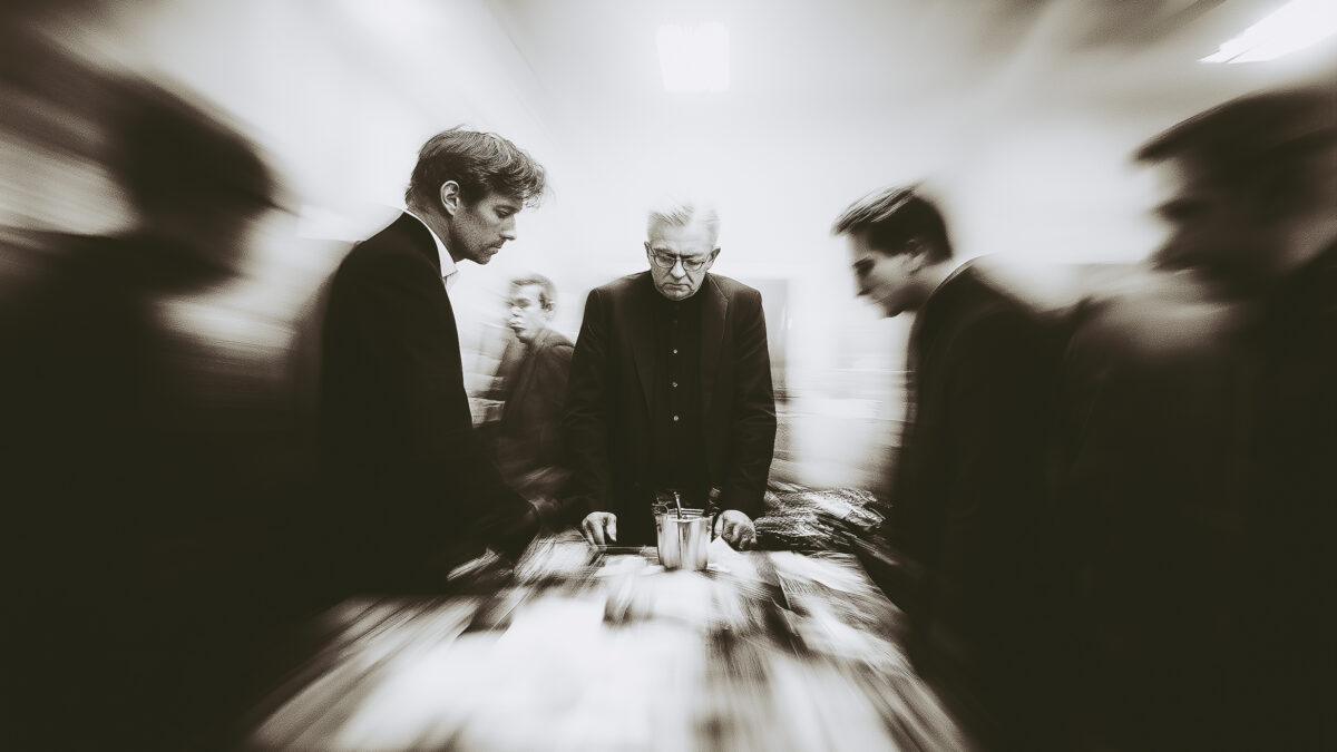 Blurred motion workplace scene with professionals around a table, highlighting one leader focused amidst motion, representing decision making under pressure.