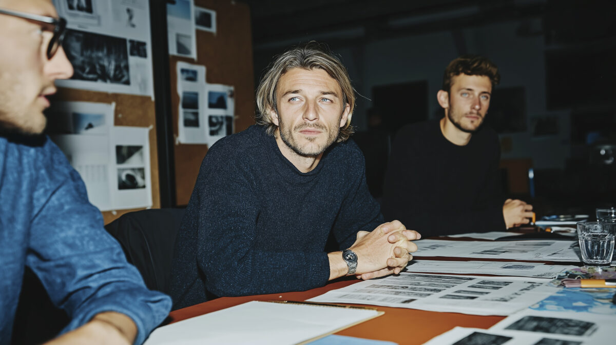 A small team in a candid meeting around a table reviewing documents, illustrating active collaboration in a workplace.