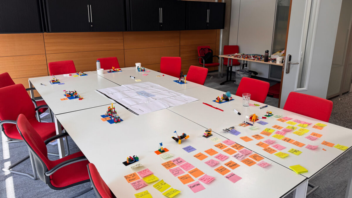 LEGO Serious Play workshop follow-up with models and prioritisation notes arranged across a conference table.