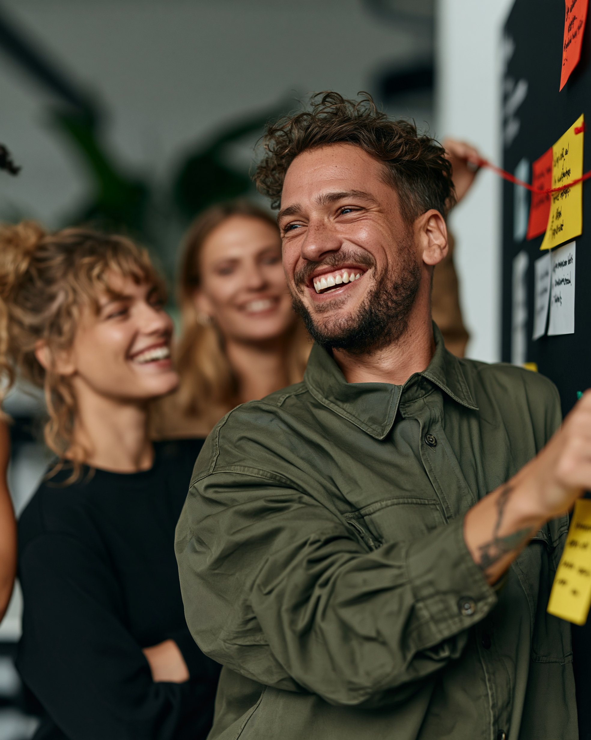 Cross-functional team laughing while mapping roles and connections on a wall during a team alignment workshop